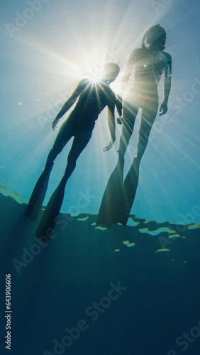 Sun and freedivers. Female freedivers float in the tropical sea against the sun. Women free divers relax on the surface of a sea