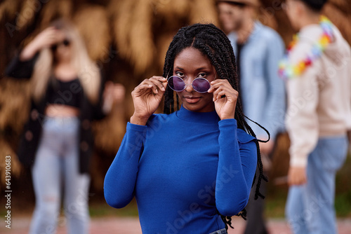 African American woman with sunglasses looking at the camera and smiling while posing at an outdoor party.