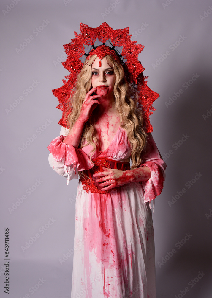 Close up portrait of scary vampire zombie queen, wearing elegant halloween fantasy costume with crown and bloody red paint splatter. Isolated on studio background with gestural hands reaching out tow Close up portrait of scary vampire zombie queen, wearing elegant halloween fantasy costume with crown and bloody red paint splatter. Isolated on studio background with gestural hands reaching out tow