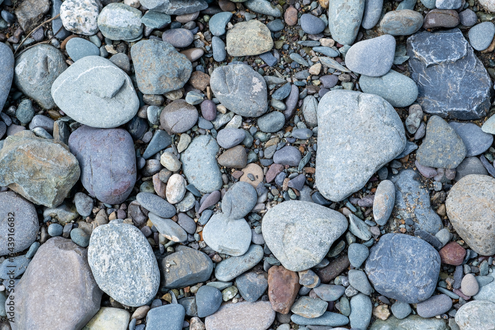 The stones were laid on the ground in the garden as a background. Background blur. Pebble stones background. Crushed stone on the seashore. Selective focus on object. The stones were laid on the ground in the garden as a background. Background blur. Pebble stones background. Crushed stone on the seashore. Selective focus on object.