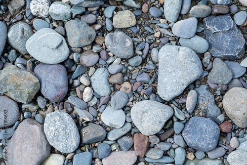 The stones were laid on the ground in the garden as a background. Background blur. Pebble stones background. Crushed stone on the seashore. Selective focus on object. 