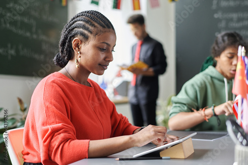Wallpaper Mural African American student using digital tablet while sitting at table with her cl