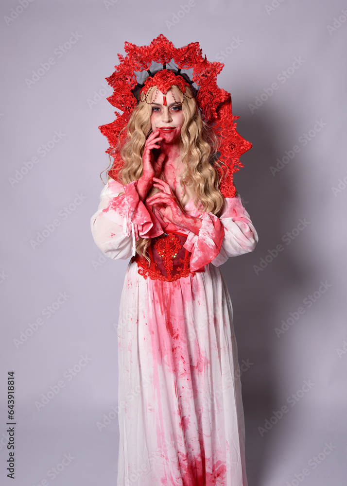 Close up portrait of scary vampire zombie queen, wearing elegant halloween fantasy costume with crown and bloody red paint splatter. Isolated on studio background with gestural hands reaching out tow Close up portrait of scary vampire zombie queen, wearing elegant halloween fantasy costume with crown and bloody red paint splatter. Isolated on studio background with gestural hands reaching out tow