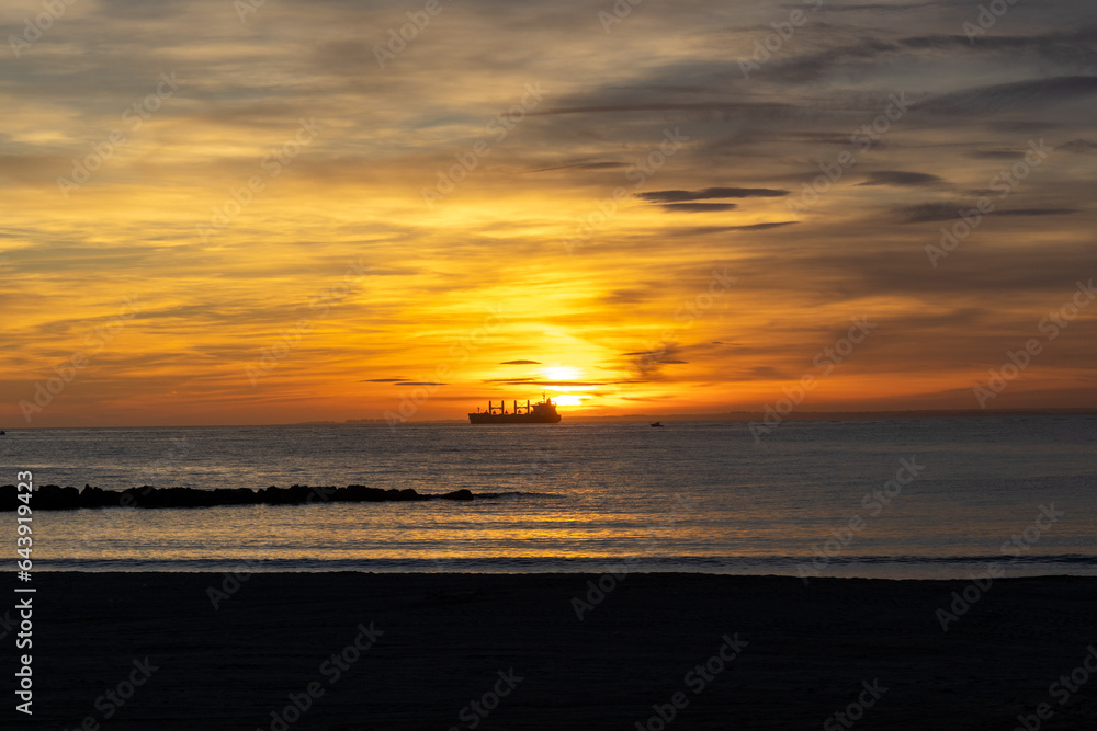 Sunset on the Zapillo beach in Almeria, Spain, ship in front of the Sun