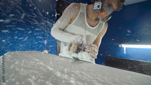 Male surfboard shaper making surfboard in his workshop. Hand shaping from blank. photo