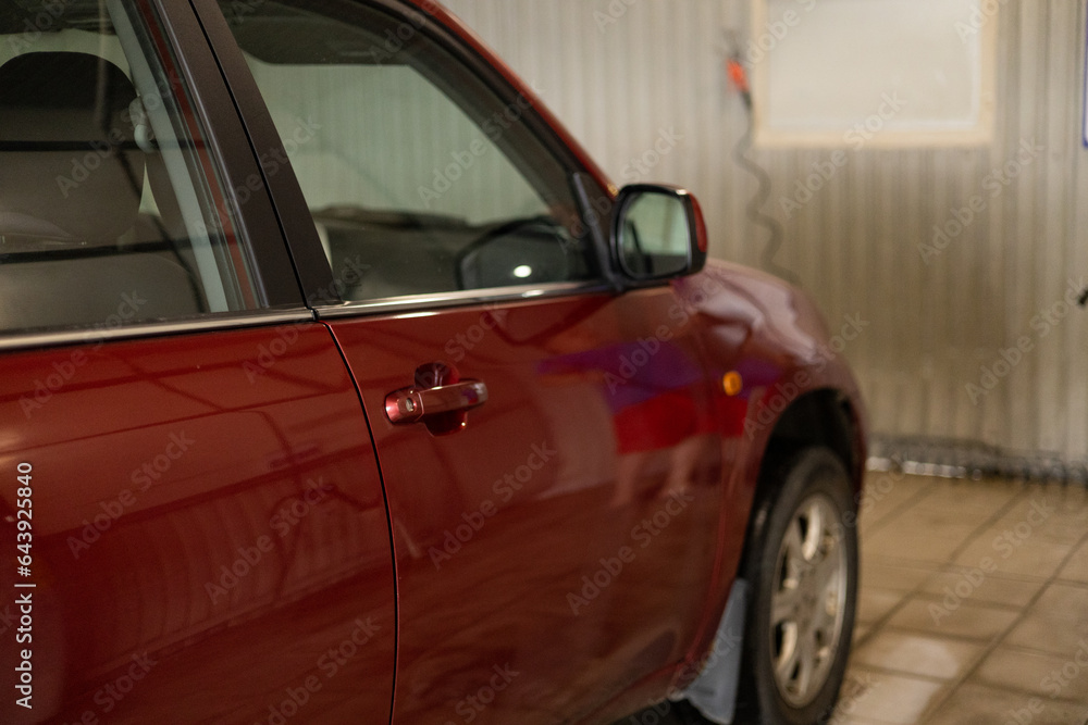The man arrived in a red car to wash it. The driver washes the car at a self-service car wash. Car wash concept.