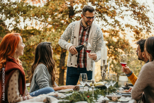 Canvastavla The essence of a memorable garden lunch, the host pouring a wine, and friends come together to create cherished moments in a picturesque outdoor setting