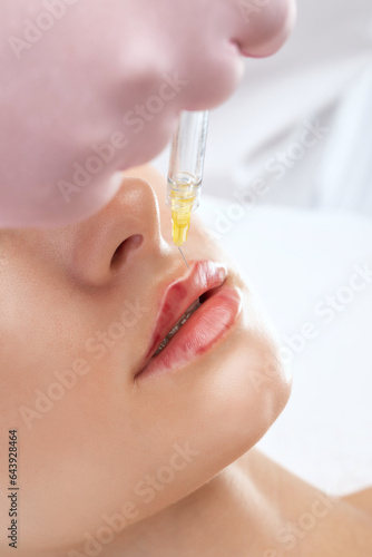 Cosmetologist does injections for lips augmentation anti wrinkle injections on the face of a beautiful woman. Female aesthetic cosmetology in a beauty salon.