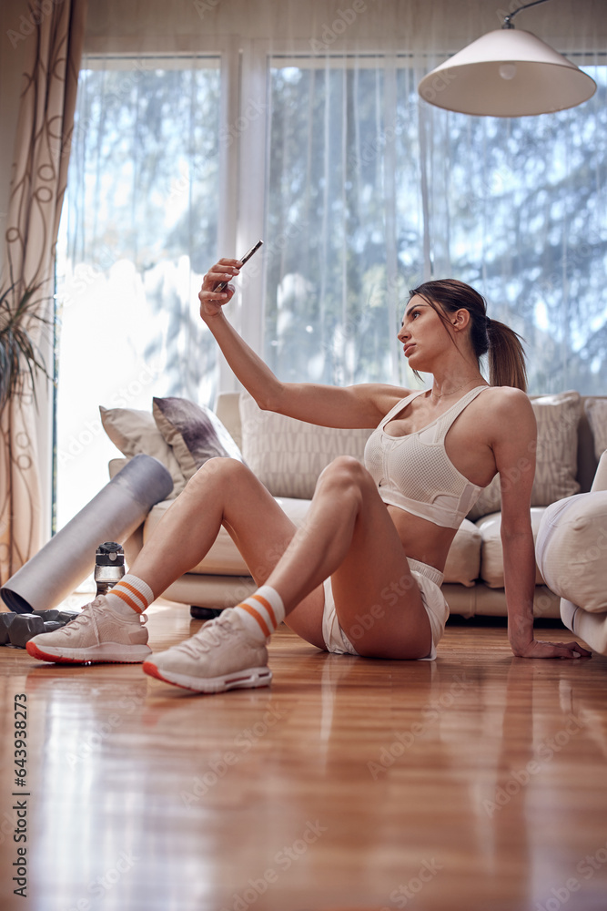 Obraz premium Sporty woman taking selfie at home during workout and exercise.