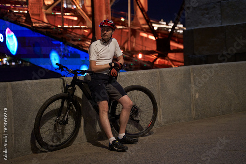 Man cyclist on the background of the night streets of the city.