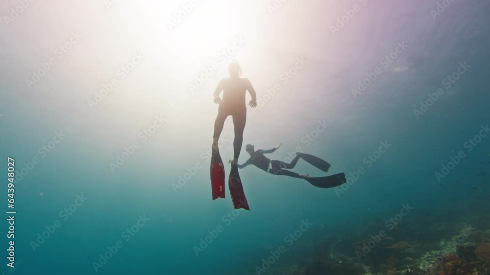 Two male freedivers glide in the tropical sea over the coral reef Two male freedivers glide in the tropical sea over the coral reef