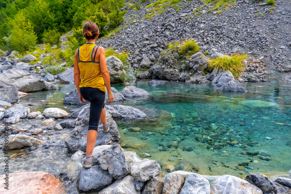A young woman in the turquoise water reservoir in the valley of Theth national park, Albania. albanian alps