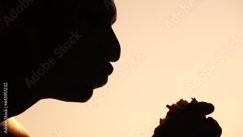 Silhouette of a man who eats a hamburger. Side view portrait of hungry person eating fatty burger with great appetite, fast food