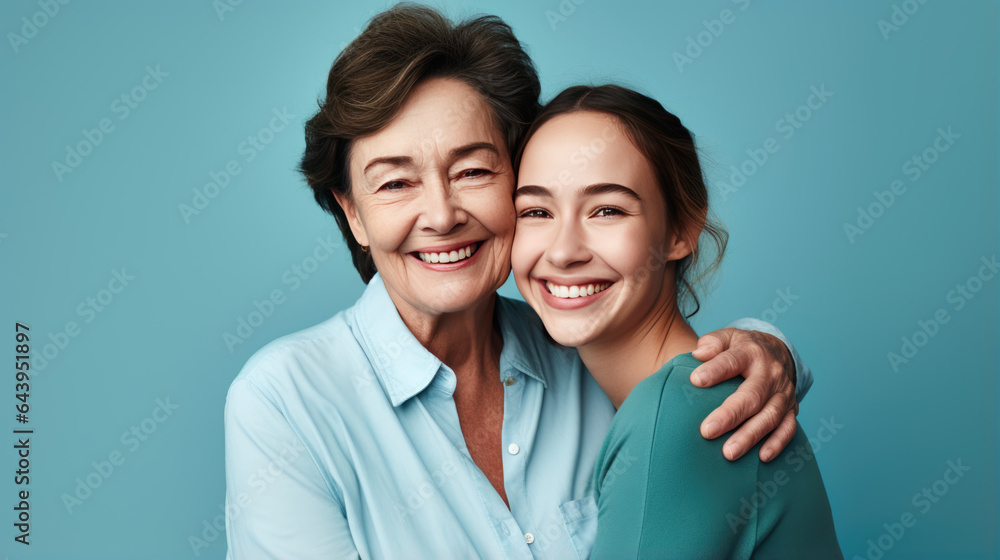Happy mother and daughter smiling and hugging against the blue background. Happy mother and daughter smiling and hugging against the blue background.