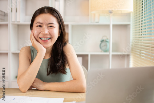 Free Download Woman using laptop to work or do homework at home with smiling face in her office, Creating happiness at work with a smile, Live performance or vdo call with laptop, Work from home. - GFXLoad