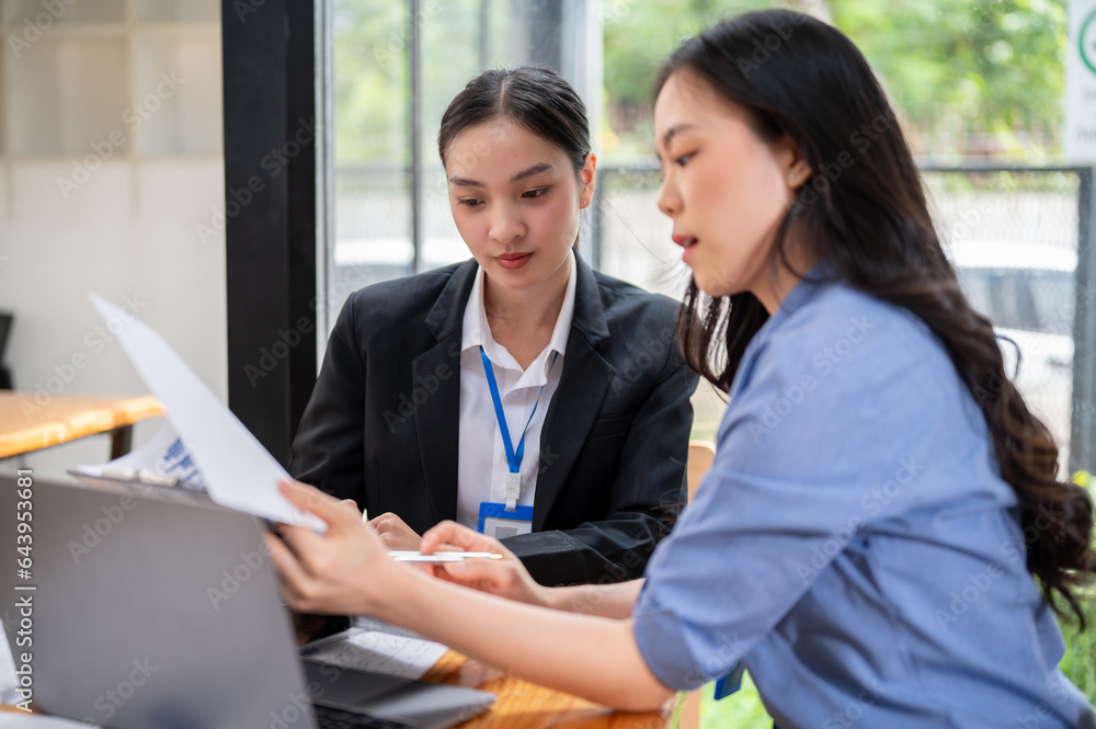 A focused Asian businesswoman is examining a business financial data report with her colleague A focused Asian businesswoman is examining a business financial data report with her colleague