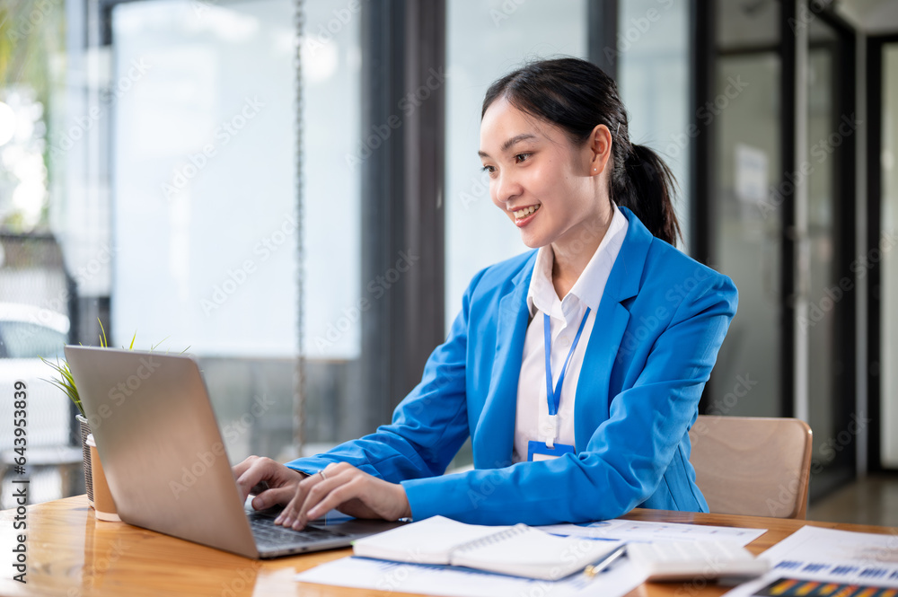 A professional and beautiful Asian businesswoman managing her work on her laptop at her desk. A professional and beautiful Asian businesswoman managing her work on her laptop at her desk.