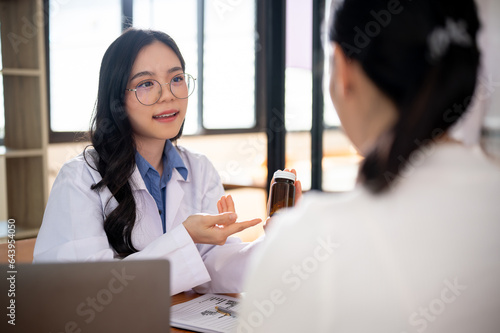 A beautiful and professional Asian female doctor is describing pills to a female patient.