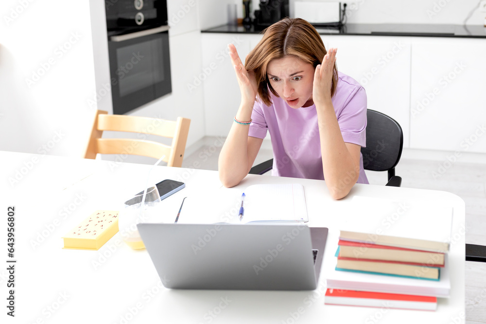 Tired and bored female student reading book and preparing for exams at university. Stack of books on the desk. Online education and learning from home concept Tired and bored female student reading book and preparing for exams at university. Stack of books on the desk. Online education and learning from home concept