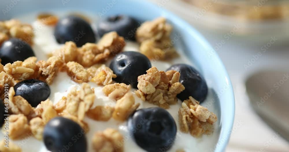 Granola with yogurt and blueberries. Cooking breakfast with muesli and berries. Healthly food. Close-up. Granola with yogurt and blueberries. Cooking breakfast with muesli and berries. Healthly food. Close-up.