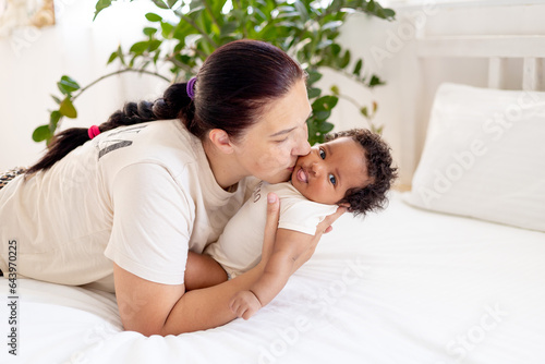 Tableau sur toile white Caucasian mom hugs and kisses an African-American black foster baby girl a
