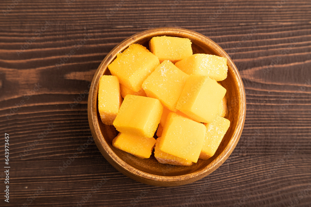 Dried mango cubes in wooden bowls on brown wooden, top view Dried mango cubes in wooden bowls on brown wooden, top view