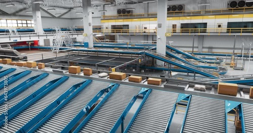 Zoom Out Footage in a Modern Delivery Station Automated Conveyor Belt System with Retail Parcels, Cardboard Boxes and Online Shopping Orders Being Sorted and Handled Before Shipping to Customers