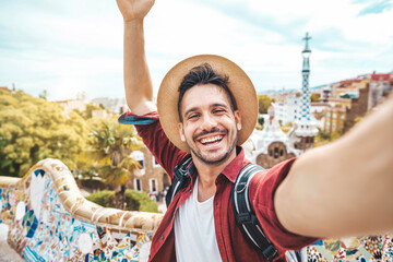 Happy tourist take selfie self-portrait with smartphone in Park Guell, Barcelona, Spain - Smiling man on vacation looking at camera - Holidays and travel concept