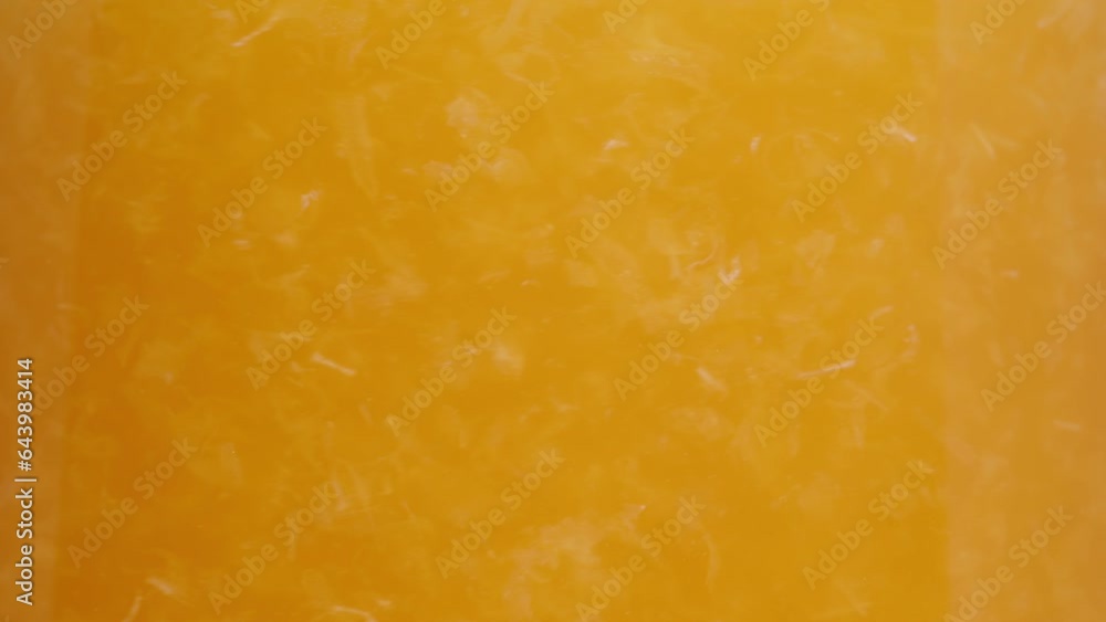 I stir the pulp in a pitcher of orange juice, on a white background, in slow motion.