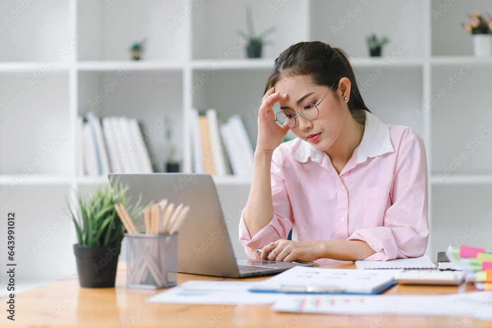 Professional millennial Accountant Woman in casuals working on financial analysis documents with a tense expression in the office.