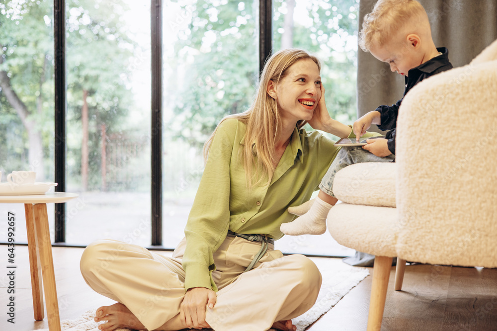 Woman sitting with her son and using tablet playing games Woman sitting with her son and using tablet playing games