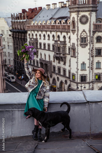 Beautiful girl with black dog on the roof at sunset in summer
