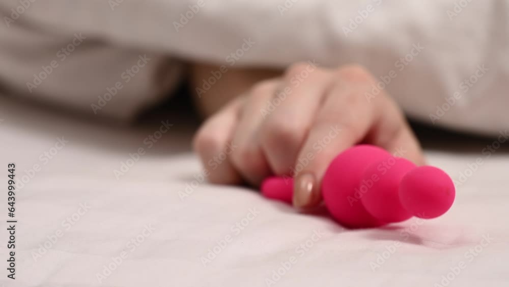 Woman takes anal beads and pulls under the covers. Woman takes anal beads and pulls under the covers.