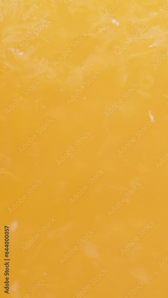 Vertical video. Orange juice with pulp, macro textures in a glass. Vertical video. Orange juice with pulp, macro textures in a glass.