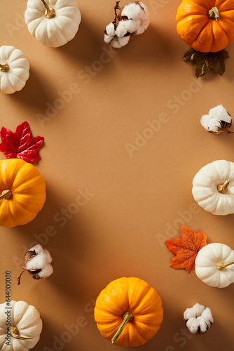 Frame of pumpkins, cotton, maple leaves on brown background. Thanksgiving vertical background. Poster template.