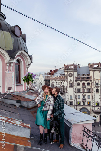 Beautiful couple in love with black dog on the roof at sunset in summer © Stanislava