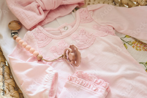 Pink outfit for a newborn girl and a pacifier