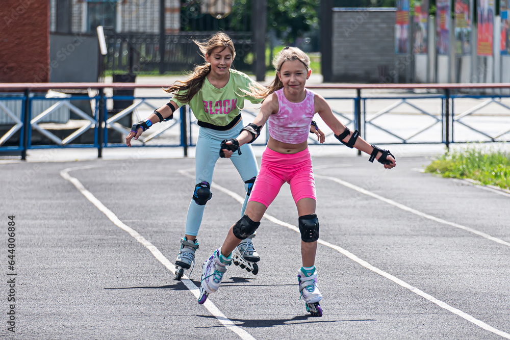 Children rollerblading at the stadium race. Speed competition. Schoolgirl in helmet rollerblading with his friend