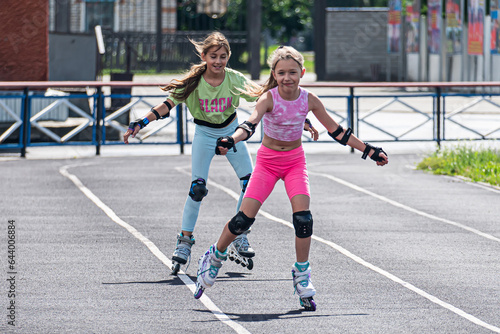 Children rollerblading at the stadium race. Speed competition. Schoolgirl in helmet rollerblading with his friend