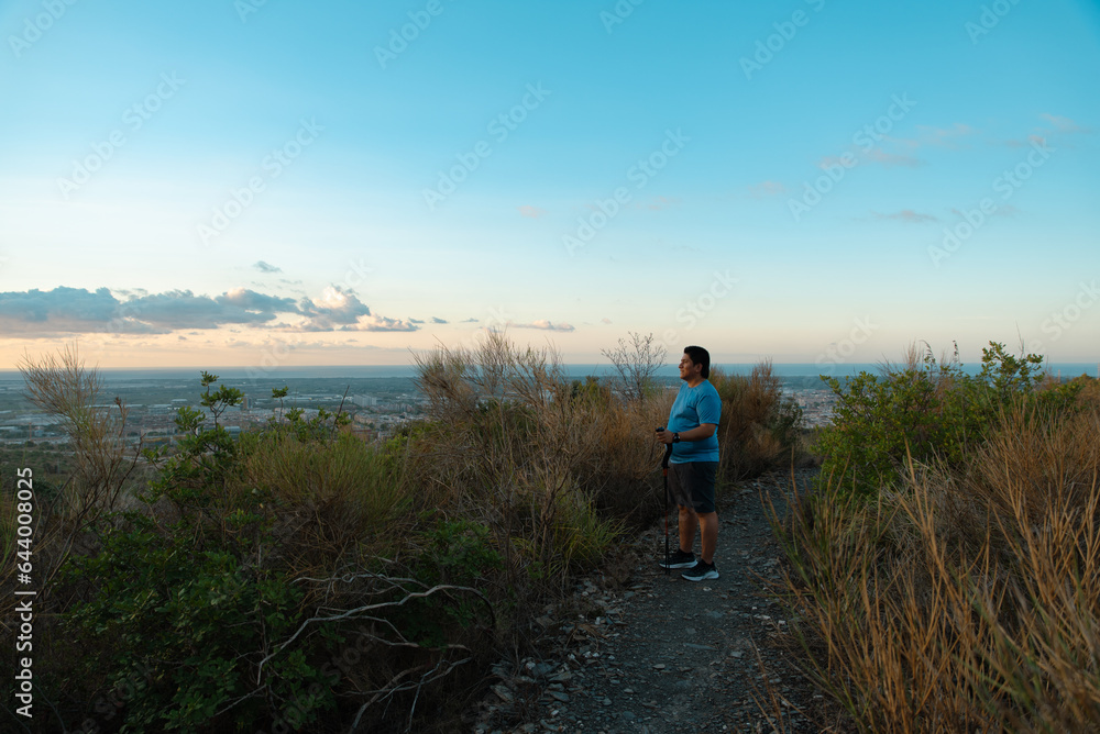 Overweight man stops his training to contemplate the landscape in the morning.