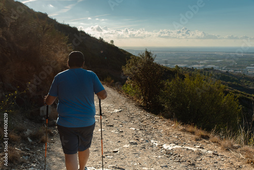 Overweight man goes down the mountain after having trained on it. photo