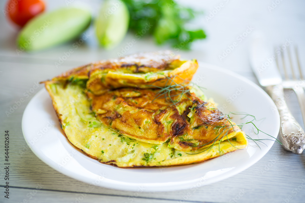 Fried omelet with zucchini, on a wooden table.