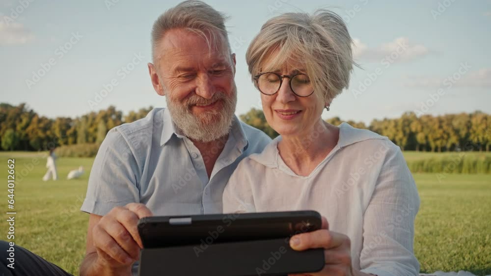 Family partners resting in park with remote gadget in hands Family partners resting in park with remote gadget in hands