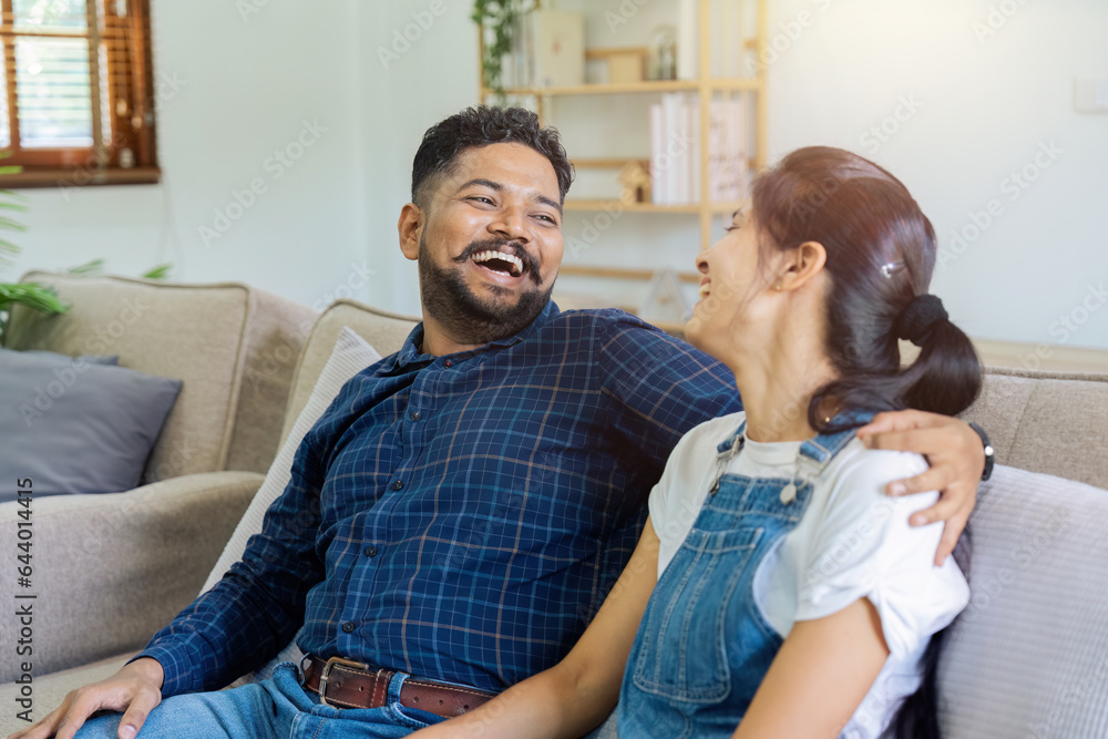 Indian couple on a sofa hugging, bonding and relaxing together in their living room Indian couple on a sofa hugging, bonding and relaxing together in their living room