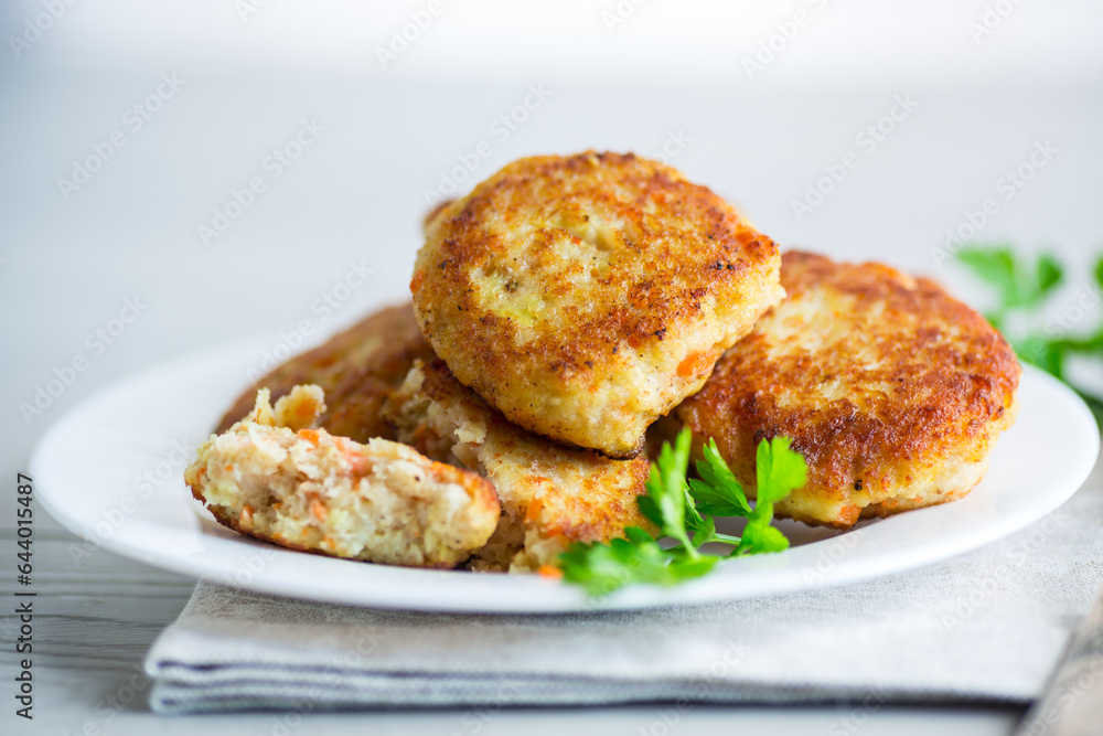 Cooked fried fish cutlets in a plate with herbs.