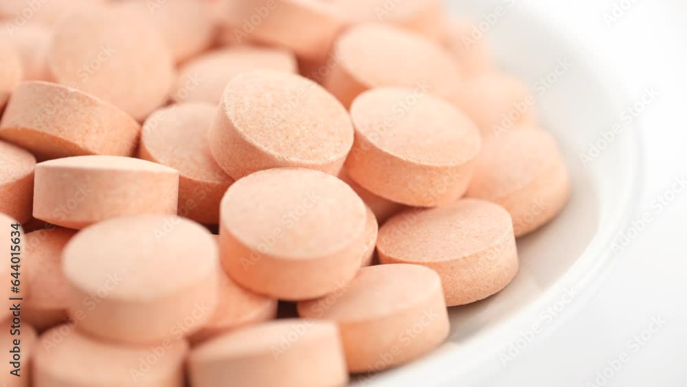 Orange pills vitamin C in white plate, rotation Orange pills vitamin C in white plate, rotation