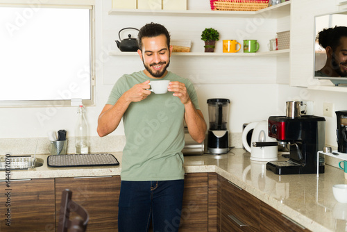 Handsome man drinking coffee enjoying domestic life in the kitchen