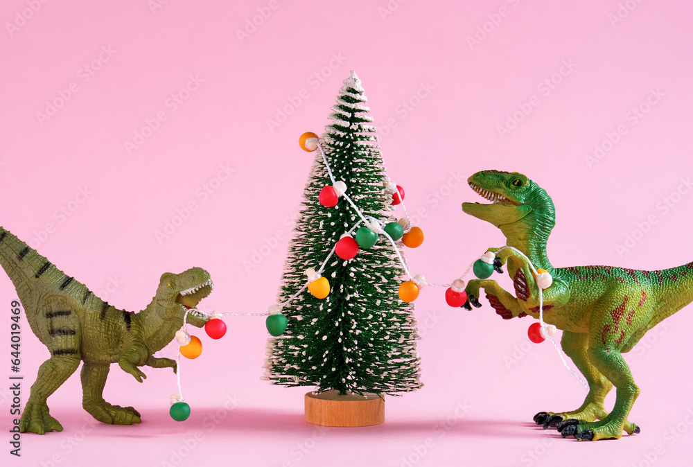 Happy cute green dinosaurs decorate Christmas tree with retro bulb garland. Christmas and new year greeting card on pastel pink background. Happy cute green dinosaurs decorate Christmas tree with retro bulb garland. Christmas and new year greeting card on pastel pink background.