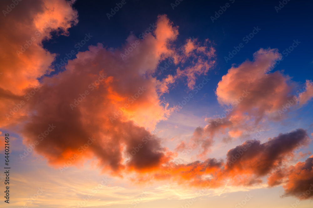 Pink clouds during sunset. Blue sky. Sunshine. A huge clouds in the sky after a storm. Natural landscape. Wallpaper and background.
