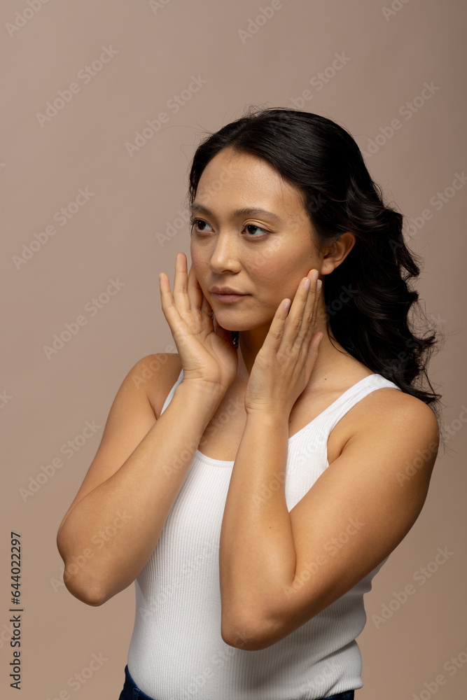 Asian woman with dark hair touching face with both hands Asian woman with dark hair touching face with both hands